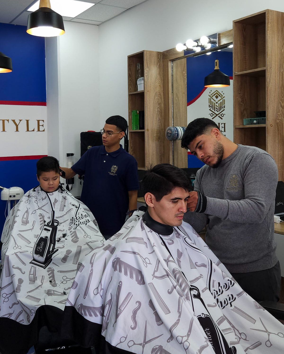 Dos barberos atendiendo clientes en Elegance Style Barbershop, Tegucigalpa